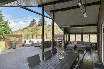 a patio with couches and chairs on a wooden deck at BL1502-Blokhus-Graevlingevej-3 in Blokhus