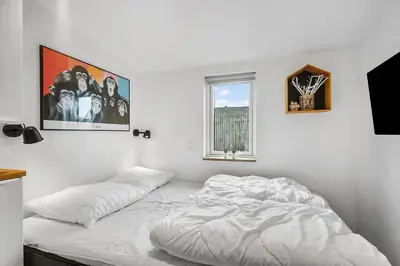 a white bedroom with a bed and a window at BL1515-Blokhus-Peder-Madsensvej-14 in Blokhus