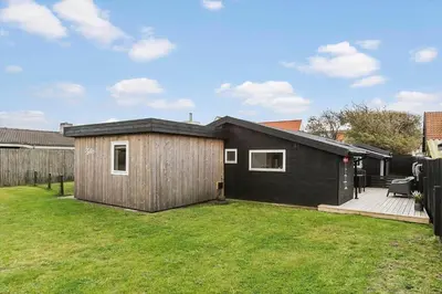 a small black house in a yard at BL1515-Blokhus-Peder-Madsensvej-14 in Blokhus