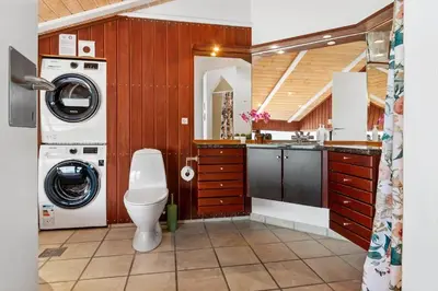 a bathroom with a toilet and a washer and dryer at BL1203-Blokhus-Pirupshvarrevej-23 in Blokhus