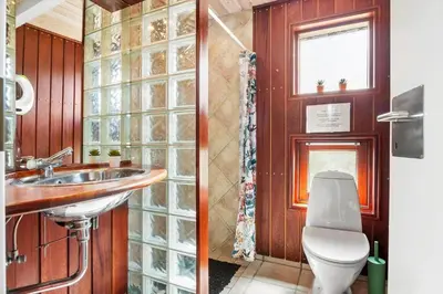 a bathroom with a toilet and a sink and a window at BL1203-Blokhus-Pirupshvarrevej-23 in Blokhus