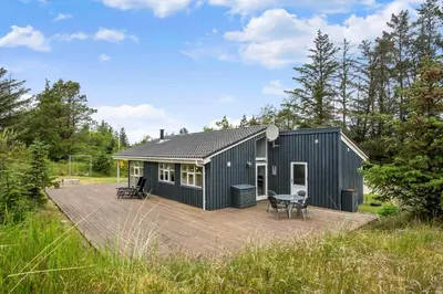 a black shed with a deck in a field at BL180-Blokhus-Soren-Petersvej-22 in Blokhus