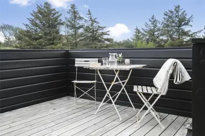 a table and two chairs on a deck at BL1556-Blokhus-Poppelvej-1 in Blokhus