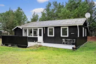 a black and white house with a porch and a table at BL488-Pandrup-Akelejevej-10 in Pandrup