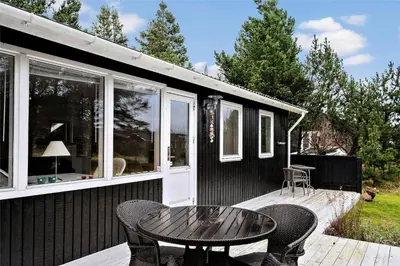 a black house with a table and chairs on a deck at BL488-Pandrup-Akelejevej-10 in Pandrup
