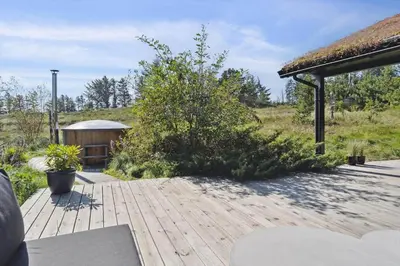 a wooden deck with a building and a bush at BL1437-Blokhus-Berberisvej-78 in Blokhus