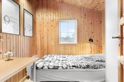 a bedroom with a bed in a wooden wall at BL1437-Blokhus-Berberisvej-78 in Blokhus