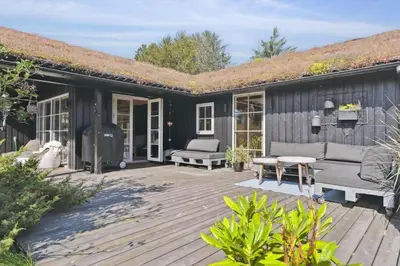 a wooden deck with a house with a roof at BL1437-Blokhus-Berberisvej-78 in Blokhus