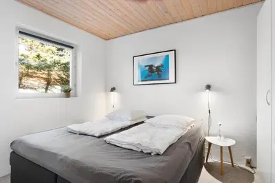 a white bedroom with a large bed and a window at BL1251-Blokhus-Vigen-9-B in Blokhus