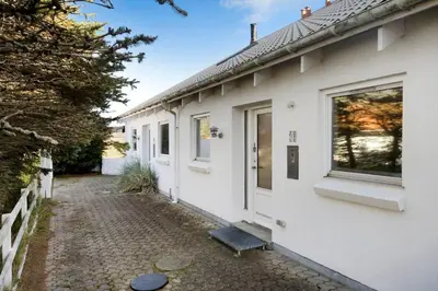 a white house with a walkway next to it at BL1251-Blokhus-Vigen-9-B in Blokhus