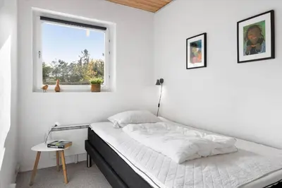 a white bedroom with a bed and a window at BL1251-Blokhus-Vigen-9-B in Blokhus