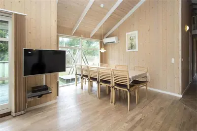 a dining room with a table and a flat screen tv at BL481-Pandrup-Rodhusparken-10 in Pandrup