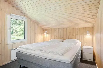 a bedroom with a large bed in a wooden wall at BL714-Saltum-Ornebjergvej-24 in Saltum