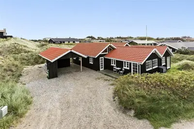 a house with a red roof on a beach at BL964-Blokhus-Klitvejen-28 in Blokhus