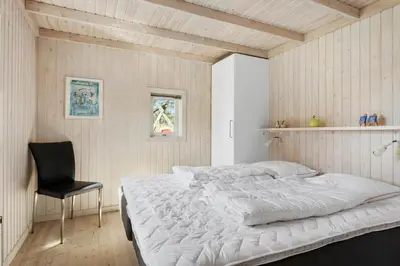 a bedroom with a large bed and a black chair at BL1600-Saltum-Daadyrvej-25-A in Saltum