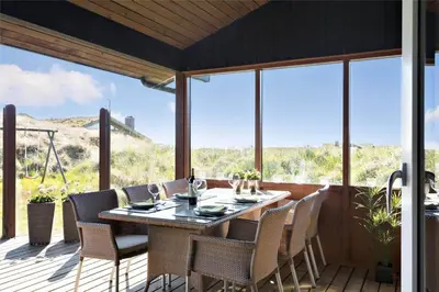a dining room with a table and chairs on a deck at BL188-Saltum-Kordalssletten-3 in Saltum