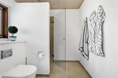 a bathroom with a toilet and a glass shower at BL1733-Blokhus-Dahl-Iversensvej-5 in Blokhus