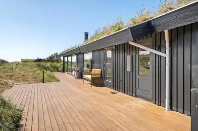 a wooden deck with a house with glass doors at BL1386-Saltum-Kordalslien-7 in Saltum