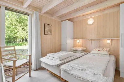 a bedroom with two beds and a chair and a window at BL226-Blokhus-Paa-Bakken-13 in Blokhus