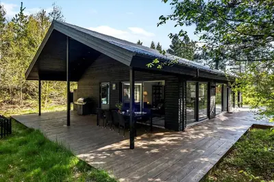 a cabin with a deck with a table and chairs at BL1266-Pandrup-Rodhusparken-58 in Pandrup