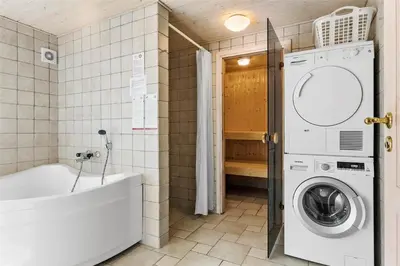 a bathroom with a washing machine and a bath tub at BL1281-Saltum-Foraarsvangen-8 in Saltum