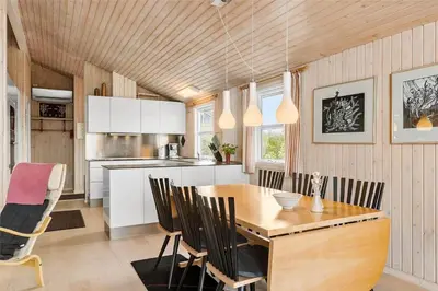 a kitchen and dining room with a wooden table and chairs at BL1281-Saltum-Foraarsvangen-8 in Saltum