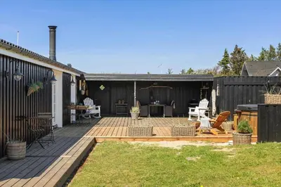 a backyard with a wooden deck with a table and chairs at BL1640-Blokhus-Solbakkevej-2 in Blokhus
