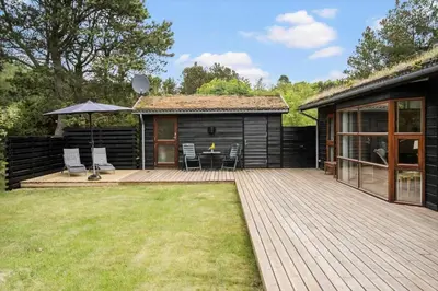a house with a deck with a table and chairs at BL100-Blokhus-Morten-Nielsensvej-19 in Blokhus