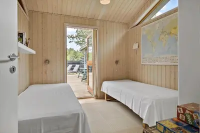a room with two beds and a door to a patio at BL100-Blokhus-Morten-Nielsensvej-19 in Blokhus