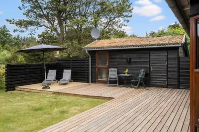 a deck with a table and chairs and an umbrella at BL100-Blokhus-Morten-Nielsensvej-19 in Blokhus