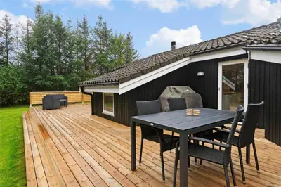 a wooden deck with a table and chairs on it at BL762-Blokhus-Berberisvej-49 in Blokhus