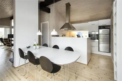 a kitchen with a white table and black chairs at BL406-Saltum-Graabakken-57 in Saltum