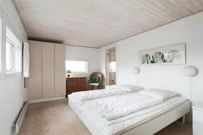 a white bedroom with a bed and a desk at BL358-Pandrup-Kaskelotten-5 in Pandrup