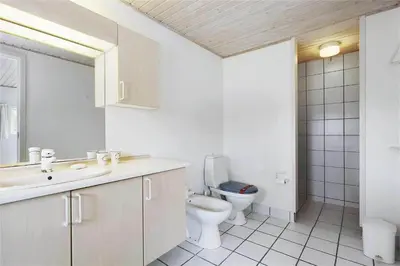 a white bathroom with a toilet and a sink at BL358-Pandrup-Kaskelotten-5 in Pandrup