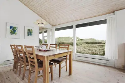 a dining room with a table and chairs and a large window at BL358-Pandrup-Kaskelotten-5 in Pandrup