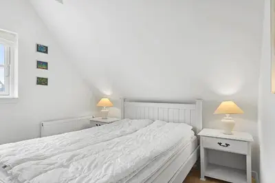 a white bedroom with a large white bed and two lamps at BL518-Blokhus-Ferren-Syd-86 in Blokhus