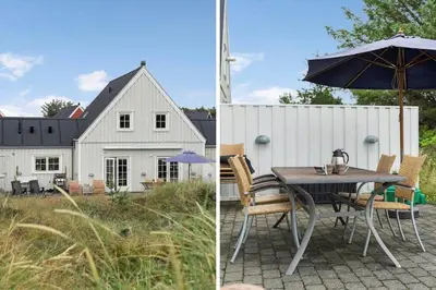 a patio with a table and an umbrella and a house at BL518-Blokhus-Ferren-Syd-86 in Blokhus
