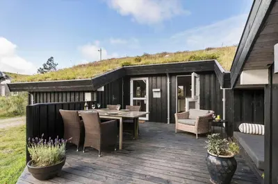 a black house with a deck with a table and chairs at BL1227-Saltum-Porsevej-31 in Saltum