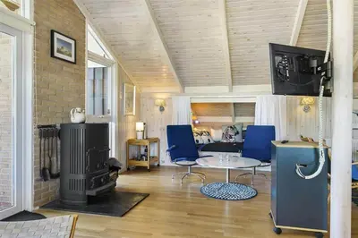 a living room with a fireplace and a table and blue chairs at BL201-Saltum-Kalundborgvej-21 in Saltum
