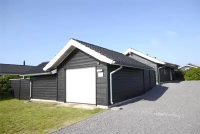 a black garage with a white door in a driveway at BL637-Blokhus-Klitvejen-35 in Blokhus