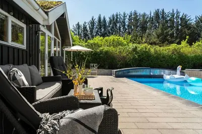 a patio with chairs and a swimming pool at BL1313-Blokhus-Bag-Hojen-3 in Blokhus