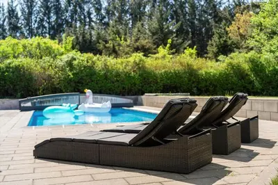 two lounge chairs sitting next to a swimming pool at BL1313-Blokhus-Bag-Hojen-3 in Blokhus