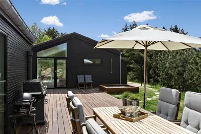 a patio with an umbrella and a wooden table at BL1777-Blokhus-Lyngbakkevej-10 in Blokhus