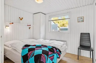 a bedroom with a bed and a black chair at BL1770-Saltum-Klittornvej-5 in Saltum