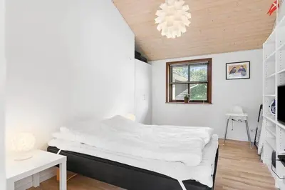 a bedroom with a large bed and a chandelier at BL1718-Blokhus-Ronliensvej-16 in Blokhus