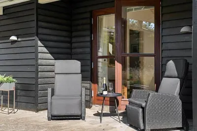 a patio with two chairs and a table and glass doors at BL1718-Blokhus-Ronliensvej-16 in Blokhus