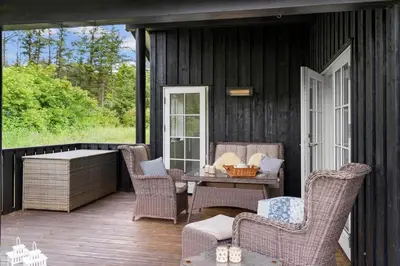 a screened in porch with wicker chairs and a table at BL653-Saltum-Nordvestvej-27 in Saltum