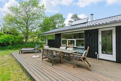 a wooden deck with a picnic table and chairs on it at BL1627-Blokhus-Lyngvej-17 in Blokhus