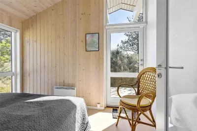 a bedroom with a bed and a chair and a window at BL809-Pandrup-Lommelaerken-20 in Pandrup