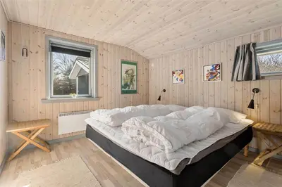 a large white bed in a room with wooden walls at BL613-Blokhus-Septimusvej-9 in Blokhus